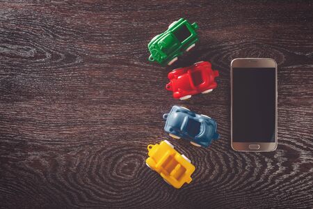 Four cars model and phone on wooden background with copyspace. concept of car rental, auto car insurance and travellingの写真素材