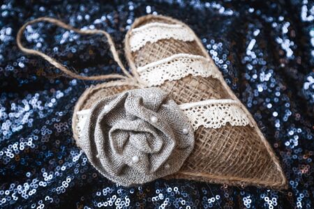 Christmas handmade sackcloth heart on dark blue blurred, sparkling and fairy background. Happy New Year and Xmas concept. handmade decor for tree, home, and interiorの写真素材