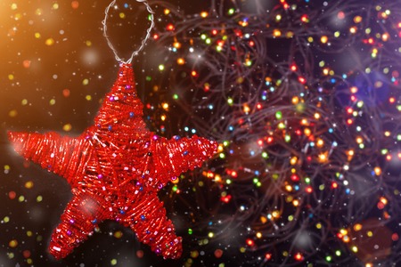 Merry Christmas handmade sackcloth toy red star. blurred background with garland, sparking, glowing and snow. Happy New Year and Xmas concept for postcard. interior decorの写真素材