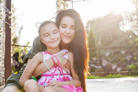 Attractive mother and daughter hugging with closen eyes and smiling. Concept of happy loving familyの写真素材