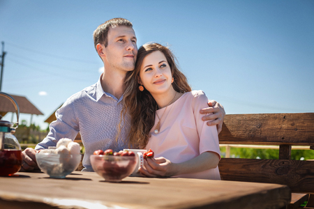 young future mom and dad resting outdoors. handsome man and cute woman drinking tea and eating strawberry, happy family conceptの写真素材