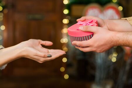 Close up shot guy giving present in hands of his girl on valentines day