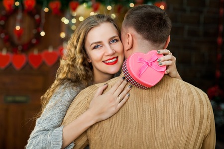 in love couple celebrate valentines day. wife with tenderness hugging husband, smiling and enjoy presentの写真素材