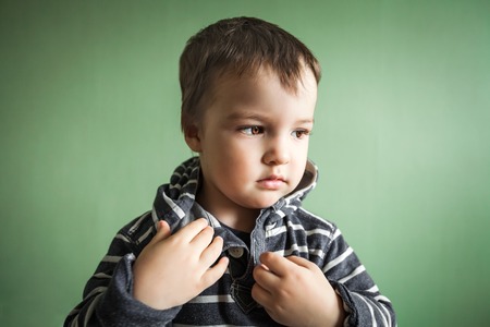 Little cute handsome boy fastening collar of stripped pullover