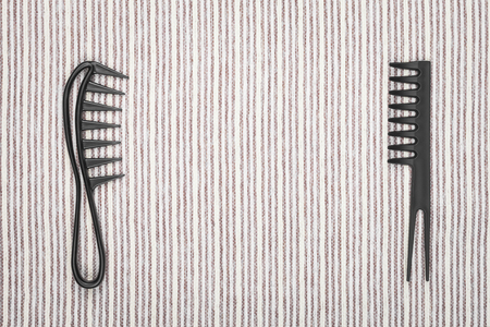 two different hairbrushes lying opposite to each other on a grey striped background.の写真素材