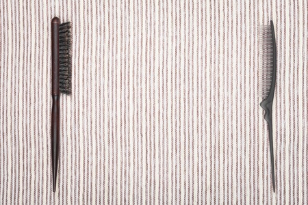 two different professional hairbrushes lying on a grey striped background.