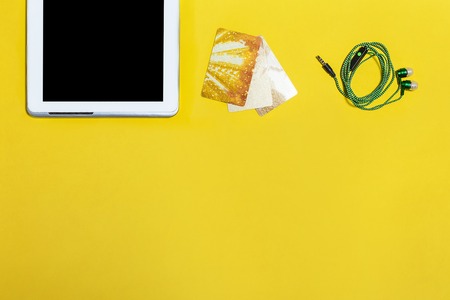 modern people attributes. gold credit cards, green earphones and a tablet. Concept of summer sale and shopping. Top view. free space for textの写真素材