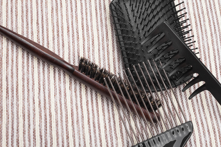 various hairbrushes lying one on one in a pile on a grey striped background. concept of professional...