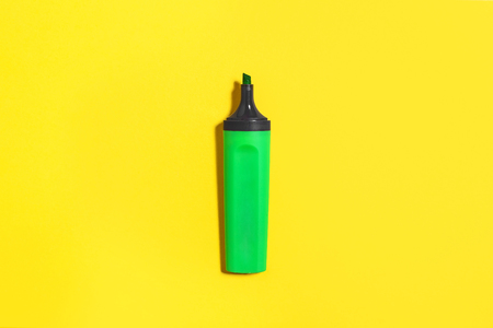 new green bright plastic marker lying on a yellow background without a cap. concept of office suppliesの写真素材