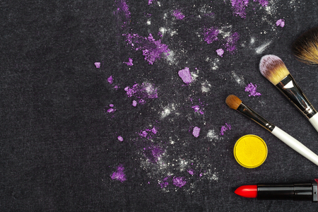 make up tools and purple loose eye shadows lying on a black cloth. concept of professional cosmetics. free space for advertisementの写真素材