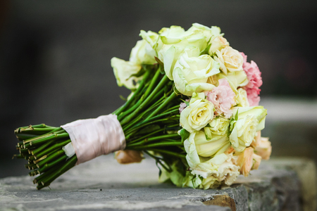 Close up photo of perfect beautiful wedding bouquet laying on the stone. bouquet includes white roses and pink peoniesの写真素材