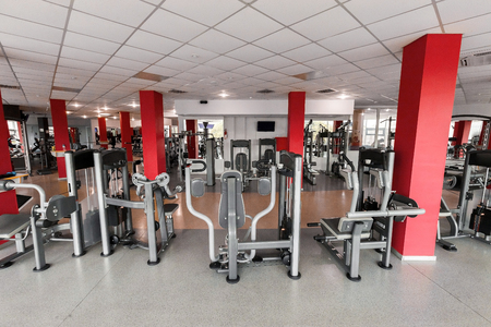Gym interior with diversity of modern equipment. light modern room with row of treadmills, mats and...
