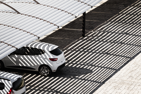 white clean cars on a parking lot in sunny summer day are under the shadows from the canopy falling onの写真素材