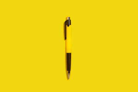 new bright plastic automatic yellow and black pen lying on a yellow background. concept of office supplies. free space for textの写真素材