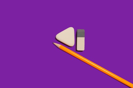 new pencil and two different in shape erasers lying on a purple background. concept of office supplies. free space for textの写真素材