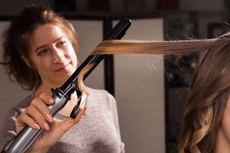 hairdresser making a hairdo with ringlets to a beautiful model in a beauty salon at a master class. concept of professional stylists studyingの写真素材