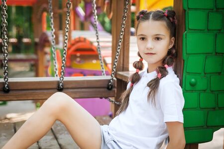 cute little thoughtful girl sitting at the playground. concept of summer, childhood and leisure.の写真素材