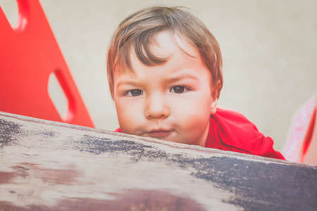 portrait of cute little boy in red t-shirt excitedly playing on playground. concept of happy healthy childの写真素材