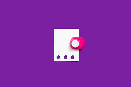 pink hole puncher with a paper on a purple backgroundの写真素材