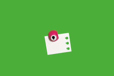 small hole puncher with a paper on a green surfaceの写真素材