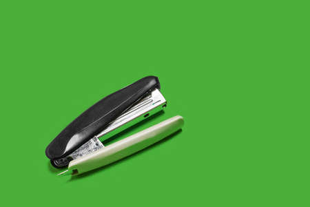black stapler isolated on a green backgroundの写真素材