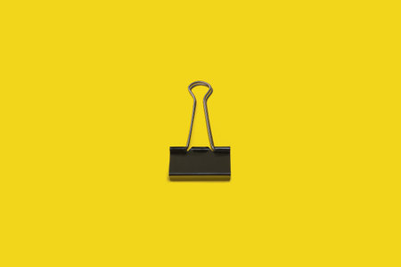 black paper clip on a yellow surfaceの写真素材