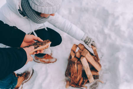 Couple put firewood to snow. Winter themeの写真素材