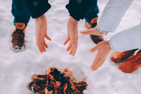 Man and woman warm their hands near fire. winter themeの写真素材