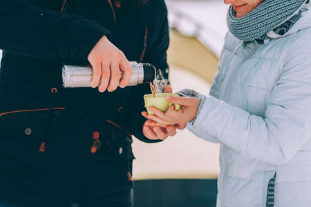 guy pour hot coffee to his girlfriend in green cup. winter hike themeの写真素材