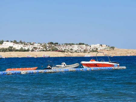 Pleasure boats at the pier of the blue sea. In the background are hotels. Holidays on the Red Seaの写真素材