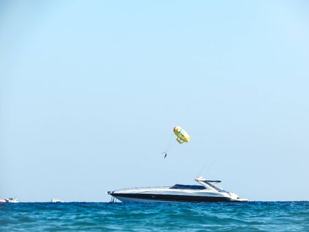 Nice vacation at sea. Yacht, blue water, clear sky and parachute over the oceanの写真素材
