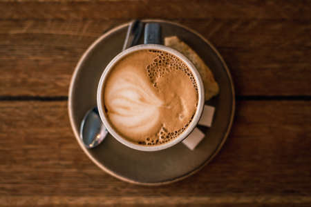 A cup of coffee on a wooden background close-up. Coffee on a platter. Coffee, biscuits, sugar and a...