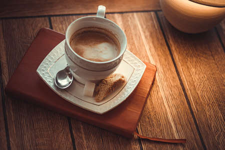A cup of coffee on the diary. Coffee and a notebook on a wooden background. A cup of coffee on a platter, a spoonful, sugar and croutons. Morning coffee on the tableの写真素材