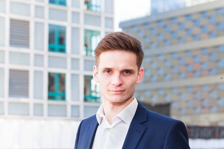 Portrait of a young businessman on a background of office buildingsの写真素材