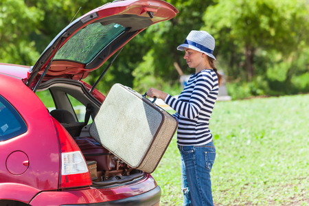 Girl happy child travel suitcases car summer landscapeの写真素材