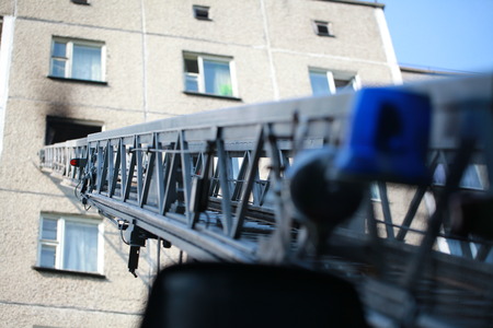 The ladder of a fire engine to a burning house