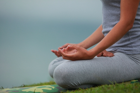Young woman is engaged in hatha yoga in the mountains in the morning in a fogの写真素材