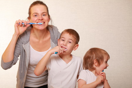 family mom and two blond boys brush their teethの写真素材
