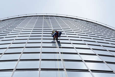 belarus, minsk, 2021 industrial climber hanging on a rope washes the windows of a tall business buildingのeditorial素材
