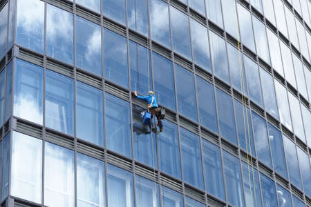 belarus, minsk, 2021 industrial climber hanging on a rope washes the windows of a tall business buildingのeditorial素材