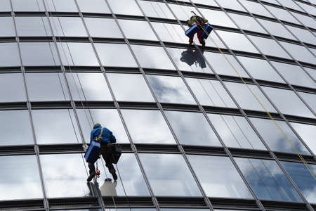 belarus, minsk, 2021 industrial climber hanging on a rope washes the windows of a tall business buildingのeditorial素材