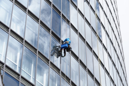 belarus, minsk, 2021 industrial climber hanging on a rope washes the windows of a tall business buildingのeditorial素材