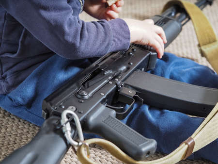 the child is playing with a weapon. a machine gun in the hands of a little boyの写真素材