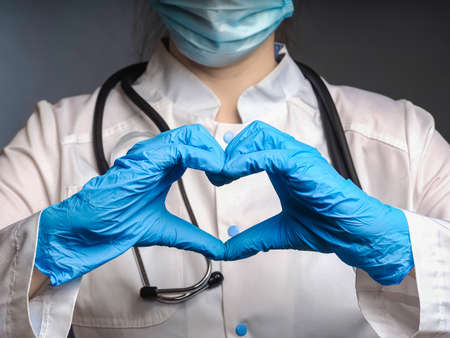doctor's hands in gloves show a heart symbol