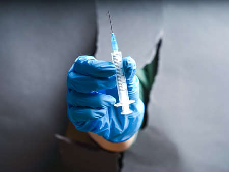 doctor's hand in a glove holds a syringeの写真素材