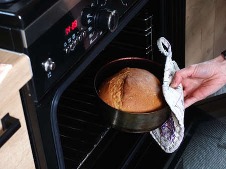 woman takes out bread baked from the oven in the kitchen