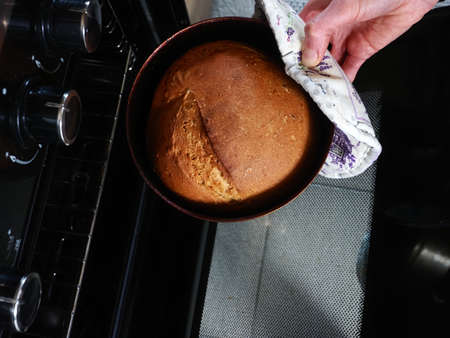 woman takes out bread baked from the oven in the kitchen