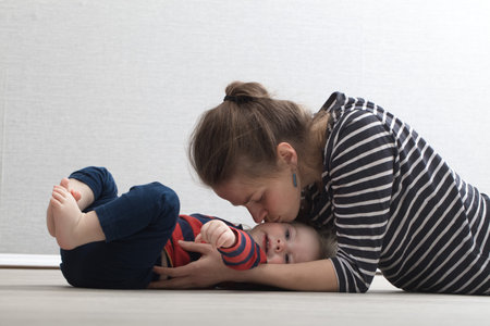 mother plays with the baby lying on the floor at home on his backの写真素材