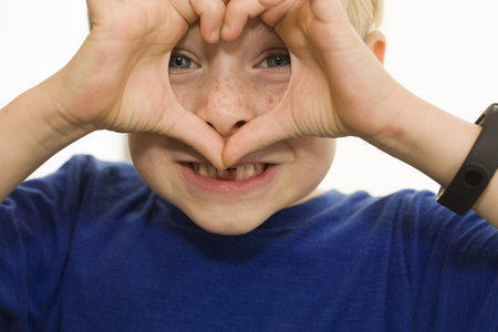 Boy making a heart shape with his fingers on a white background.の写真素材