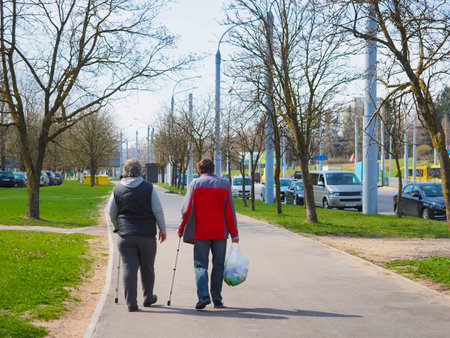Elderly couple with crutches walking in the park.の写真素材